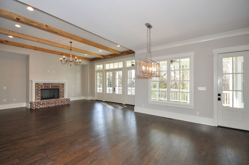 This is an example of a mid-sized country formal open concept living room in Atlanta with white walls, dark hardwood floors, a standard fireplace, a brick fireplace surround, no tv and brown floor.
