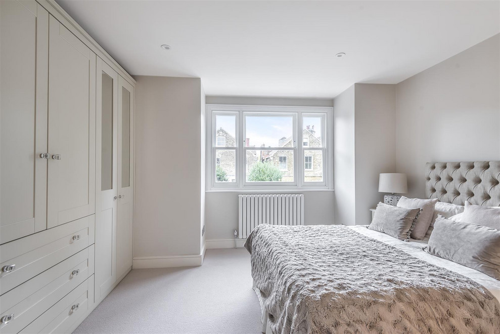 Photo of a mid-sized traditional master bedroom in London with beige walls, carpet and beige floor.