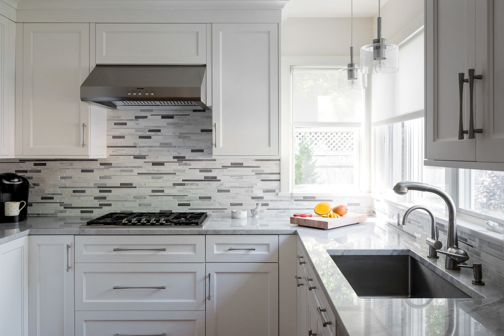 Design ideas for a transitional kitchen in Boston with an undermount sink, shaker cabinets, white cabinets, granite benchtops, white splashback, mosaic tile splashback and stainless steel appliances.