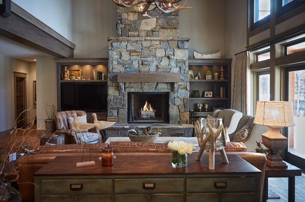 Photo of a country open concept living room in Grand Rapids with brown walls, medium hardwood floors, a standard fireplace, a stone fireplace surround and a built-in media wall.