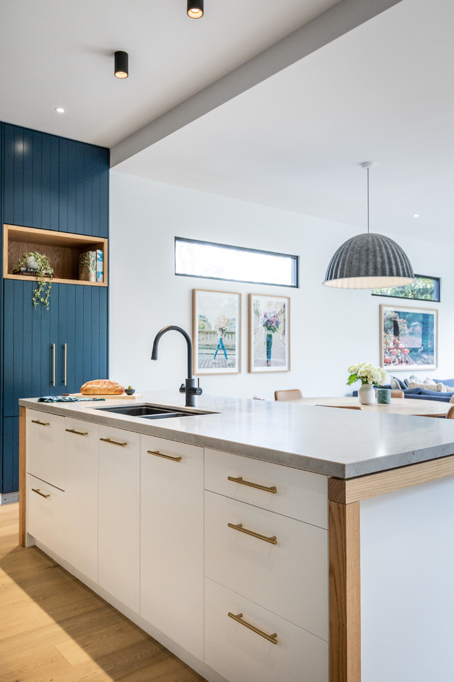 Contemporary galley kitchen in Sydney with an undermount sink, quartz benchtops, marble splashback, black appliances, light hardwood floors, multiple islands and multi-coloured benchtop.