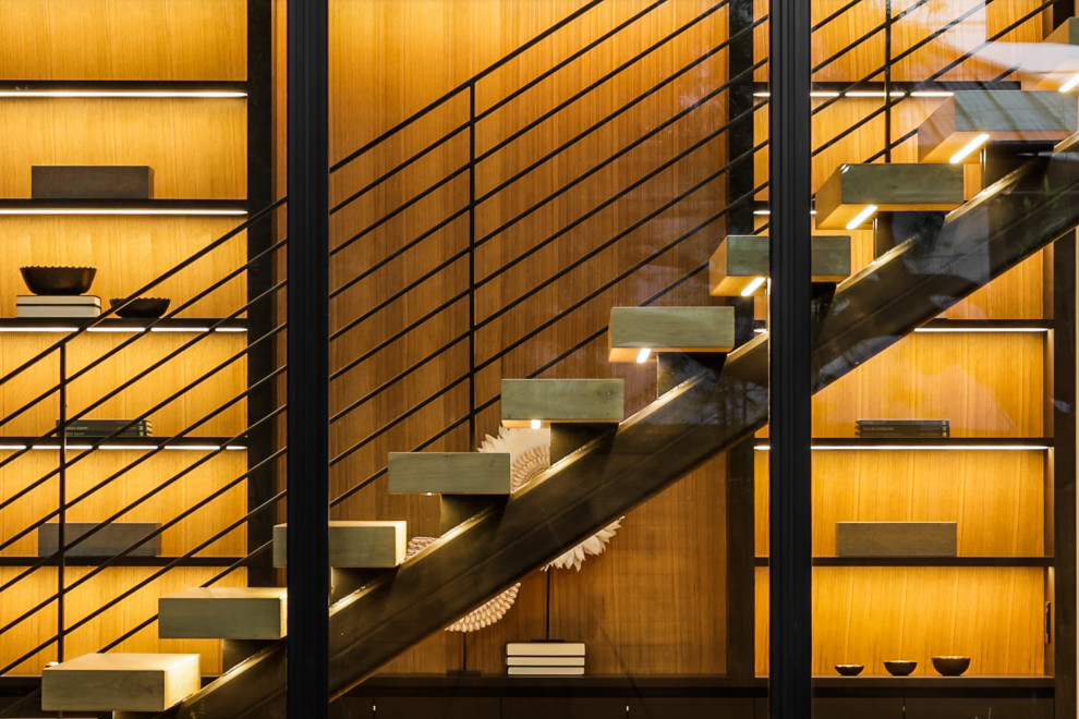 На фото: большая деревянная лестница на больцах в современном стиле с деревянными ступенями, металлическими перилами и деревянными стенами