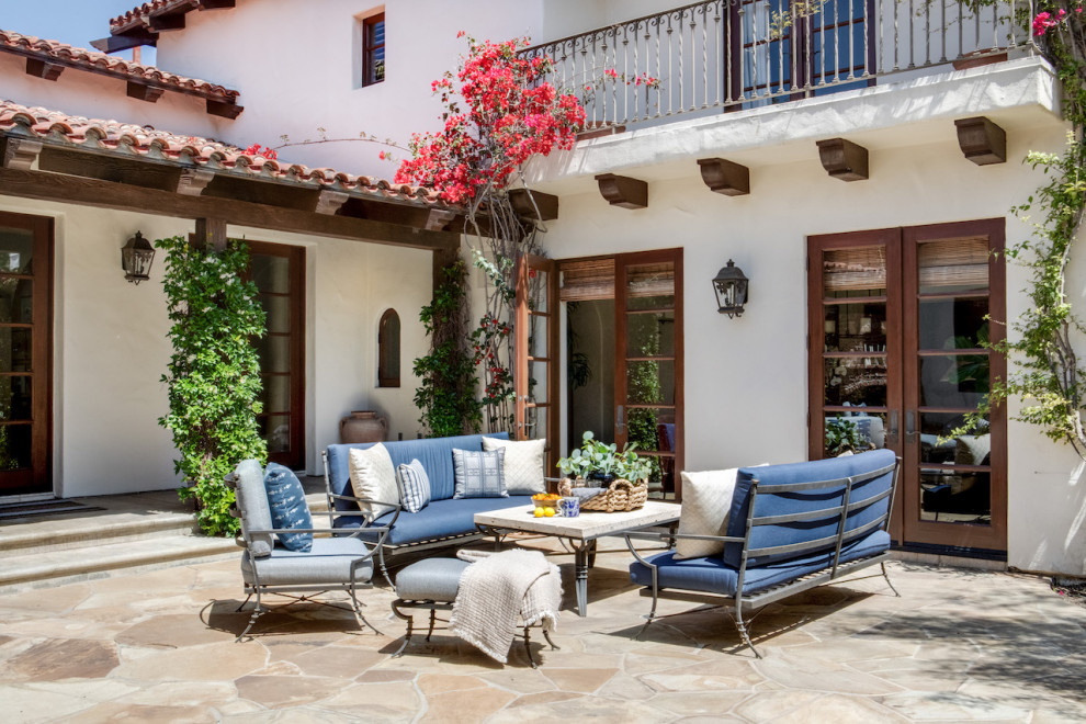 Large mediterranean courtyard patio in Orange County with with fireplace, natural stone pavers and no cover.