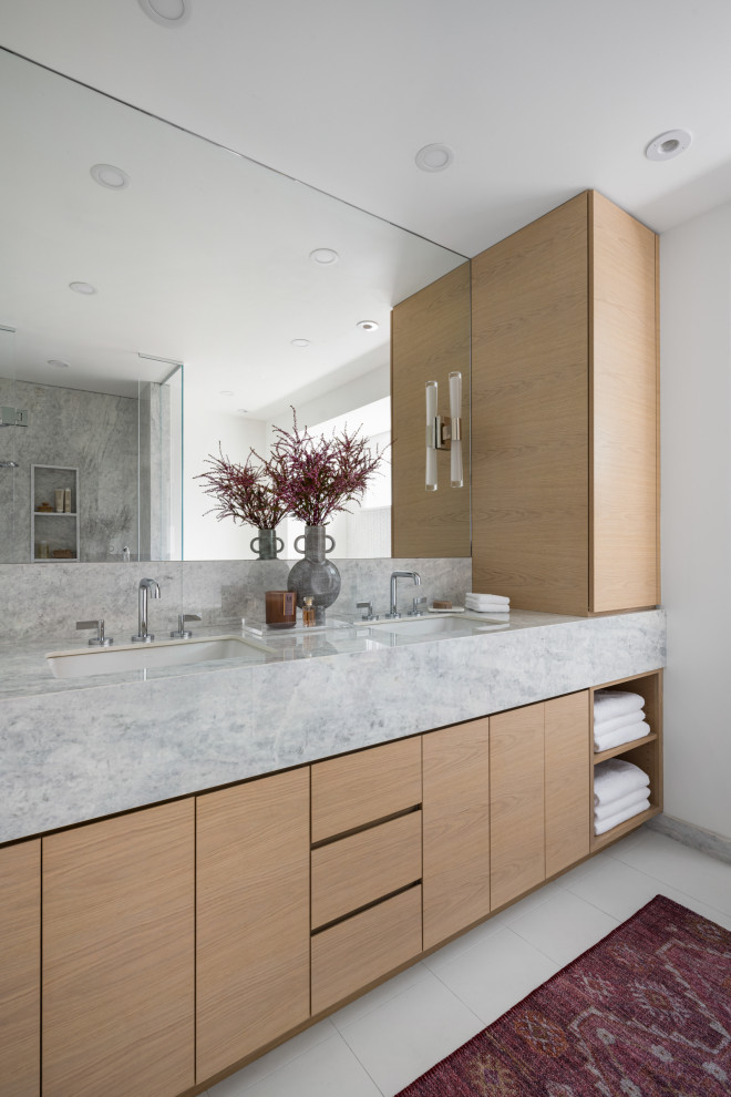 Mid-sized modern master bathroom in Minneapolis with flat-panel cabinets, light wood cabinets, a freestanding tub, a corner shower, a one-piece toilet, white tile, marble, white walls, porcelain floors, an undermount sink, marble benchtops, white floor, a hinged shower door, grey benchtops, a niche, a double vanity and a built-in vanity.