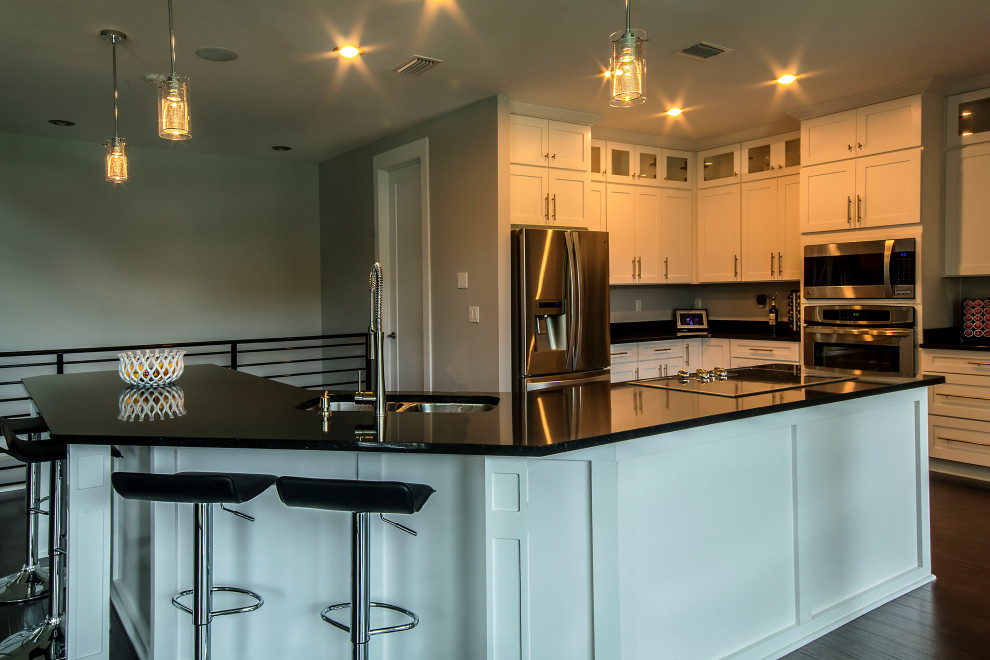 Large l-shaped eat-in kitchen photo with an undermount sink, shaker cabinets, white cabinets, granite countertops, an island and black countertops