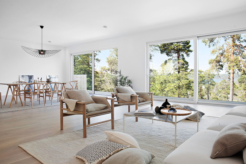Large contemporary open concept living room in Stockholm with white walls, light hardwood floors and beige floor.