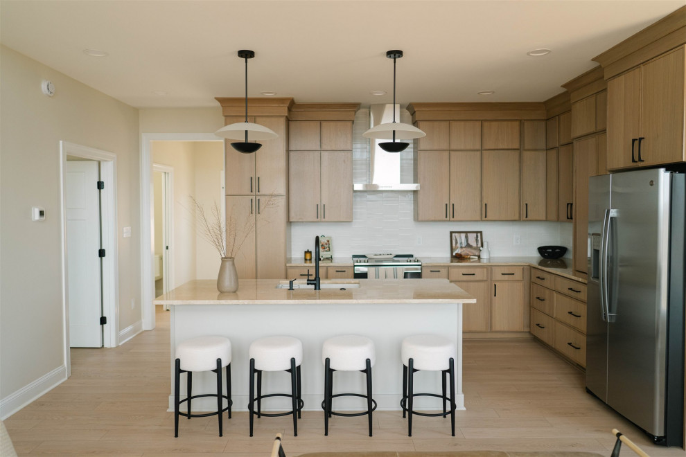 Kitchen - transitional l-shaped light wood floor and beige floor kitchen idea with an undermount sink, flat-panel cabinets, medium tone wood cabinets, white backsplash, stainless steel appliances, an island and beige countertops