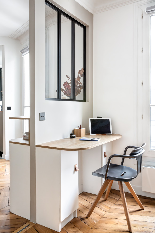 Mittelgroßes Modernes Lesezimmer ohne Kamin mit weißer Wandfarbe, hellem Holzboden, Einbau-Schreibtisch und braunem Boden in Paris