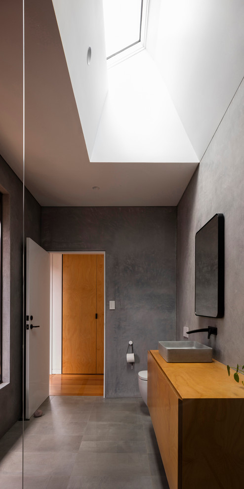 Design ideas for a modern 3/4 bathroom in Sydney with flat-panel cabinets, medium wood cabinets, a one-piece toilet, gray tile, grey walls, a vessel sink, wood benchtops, grey floor and brown benchtops.