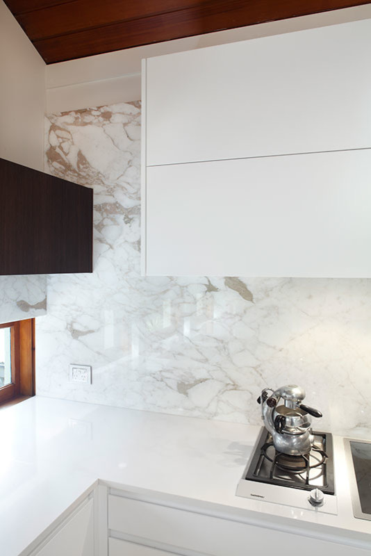 Inspiration for a large modern single-wall open plan kitchen in Sydney with a single-bowl sink, flat-panel cabinets, dark wood cabinets, marble benchtops, multi-coloured splashback, mirror splashback, stainless steel appliances, travertine floors and multiple islands.