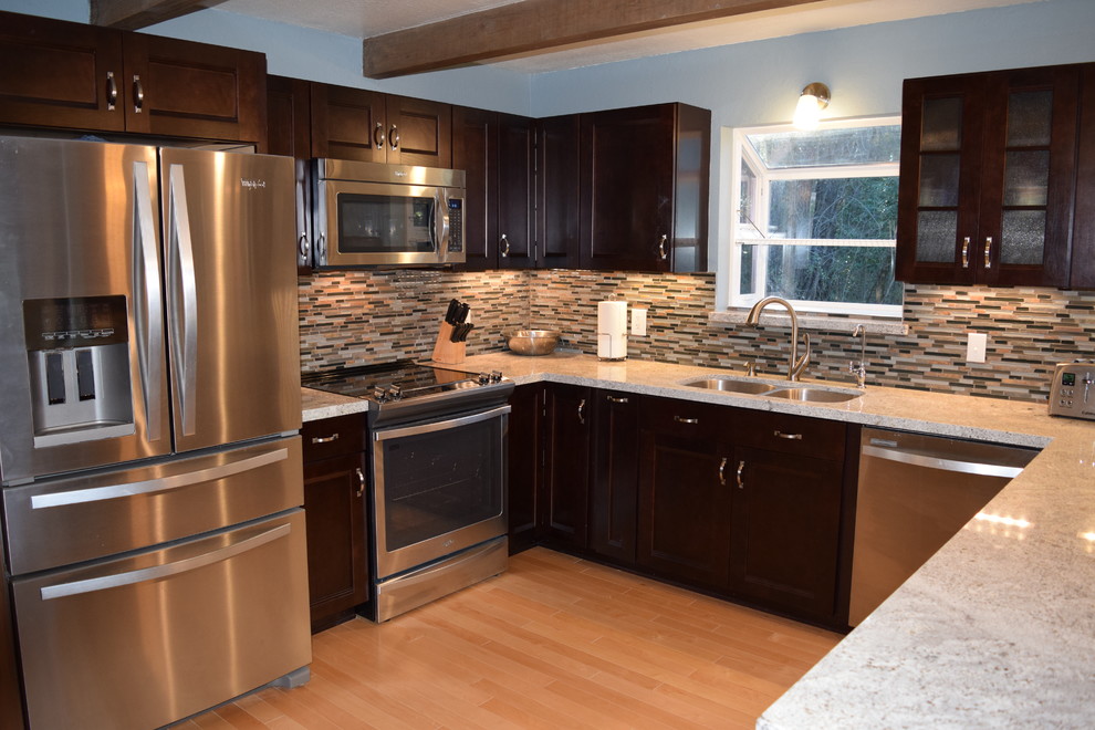 Inspiration for a mid-sized rustic u-shaped light wood floor eat-in kitchen remodel with an undermount sink, recessed-panel cabinets, dark wood cabinets, granite countertops, multicolored backsplash, stainless steel appliances and a peninsula