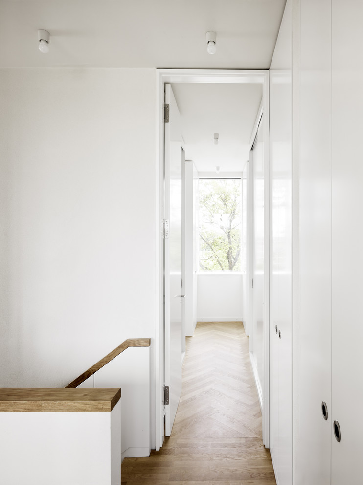 Photo of a small contemporary hallway in Berlin with white walls and medium hardwood floors.