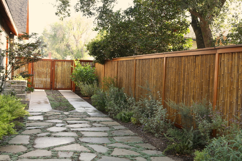 This is an example of a mid-sized asian backyard full sun formal garden in Orange County with a garden path and natural stone pavers.