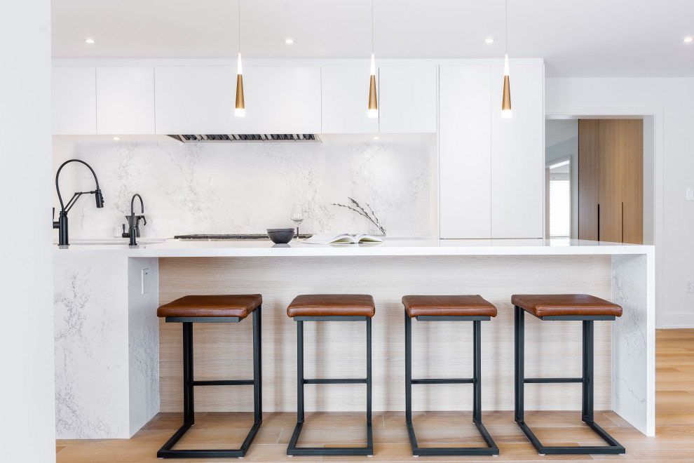 Photo of a large contemporary l-shaped eat-in kitchen in Toronto with an undermount sink, flat-panel cabinets, white cabinets, quartz benchtops, white splashback, engineered quartz splashback, stainless steel appliances, porcelain floors, with island and white benchtop.