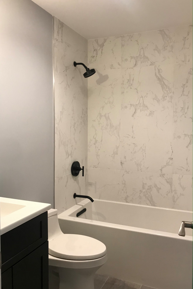 Inspiration for a small modern kids bathroom in New York with shaker cabinets, black cabinets, an alcove tub, a shower/bathtub combo, a one-piece toilet, grey walls, porcelain floors, an integrated sink, grey floor, white benchtops, a niche, a single vanity and a freestanding vanity.