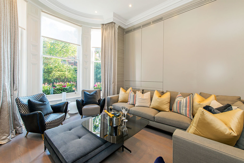 This is an example of a contemporary living room in London with beige walls and light hardwood floors.