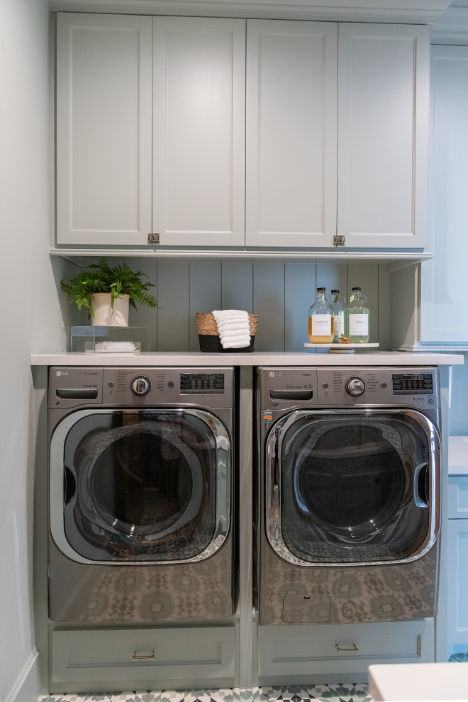 Mid-sized country u-shaped dedicated laundry room in Houston with a drop-in sink, recessed-panel cabinets, grey cabinets, grey splashback, shiplap splashback, grey walls, porcelain floors, a side-by-side washer and dryer, multi-coloured floor and white benchtop.