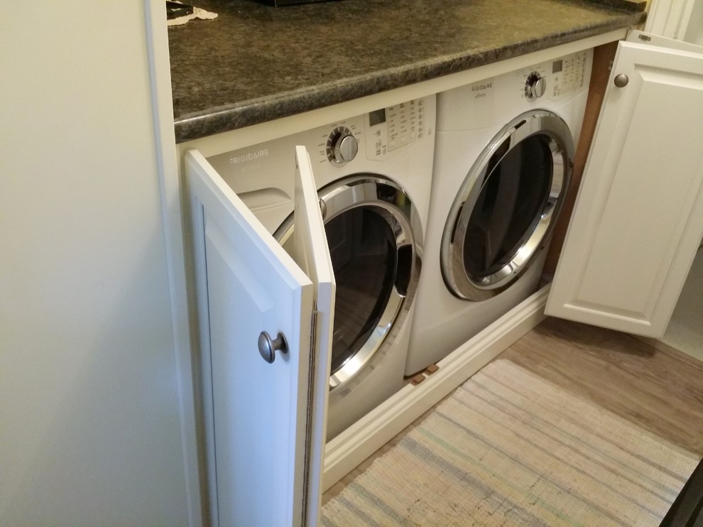 Modelo de armario lavadero tradicional pequeño con armarios con paneles con relieve, puertas de armario blancas y lavadora y secadora juntas