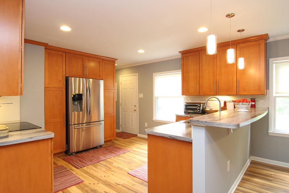 Example of a large transitional u-shaped medium tone wood floor eat-in kitchen design with a drop-in sink, recessed-panel cabinets, medium tone wood cabinets, laminate countertops, white backsplash, ceramic backsplash, stainless steel appliances and a peninsula
