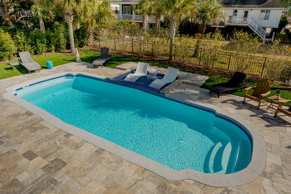 Ejemplo de piscina marinera de tamaño medio en patio trasero con adoquines de piedra natural