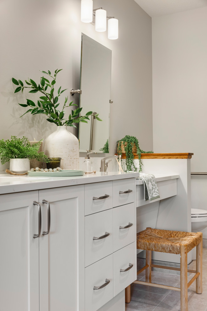 Photo of a large traditional ensuite bathroom in Minneapolis with shaker cabinets, white cabinets, a built-in shower, a one-piece toilet, porcelain tiles, white walls, porcelain flooring, a submerged sink, engineered stone worktops, a hinged door, white worktops, double sinks, a built in vanity unit, a wall niche, grey tiles and grey floors.