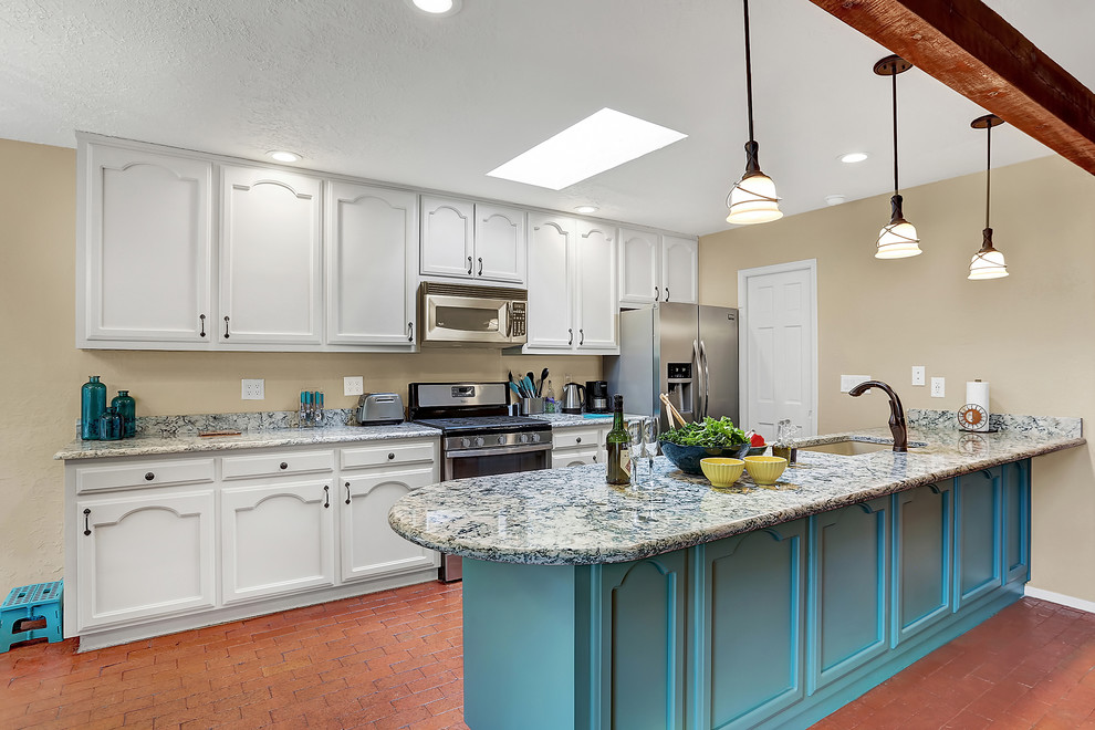 Photo of a mid-sized traditional galley open plan kitchen in Albuquerque with an undermount sink, recessed-panel cabinets, turquoise cabinets, quartz benchtops, stainless steel appliances, brick floors and with island.