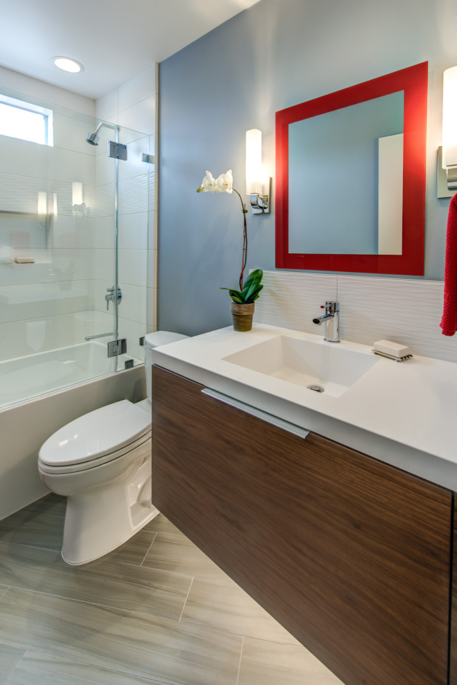 Photo of a mid-sized asian bathroom in San Francisco with flat-panel cabinets, brown cabinets, an alcove tub, a shower/bathtub combo, a two-piece toilet, white tile, ceramic tile, blue walls, porcelain floors, an integrated sink, solid surface benchtops, grey floor, an open shower, white benchtops, a niche, a single vanity and a floating vanity.