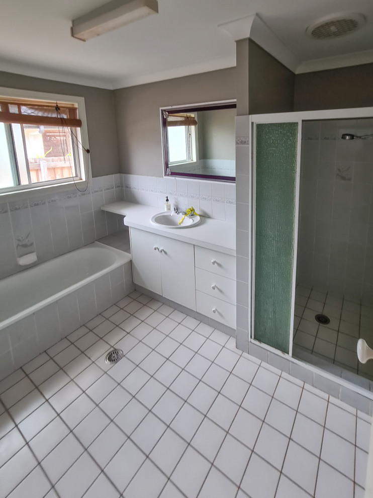 Large coastal ensuite bathroom in Other with light wood cabinets, a freestanding bath, a walk-in shower, multi-coloured tiles, ceramic tiles, white walls, porcelain flooring, a vessel sink, solid surface worktops, white floors, an open shower, white worktops, a wall niche, a single sink and a floating vanity unit.