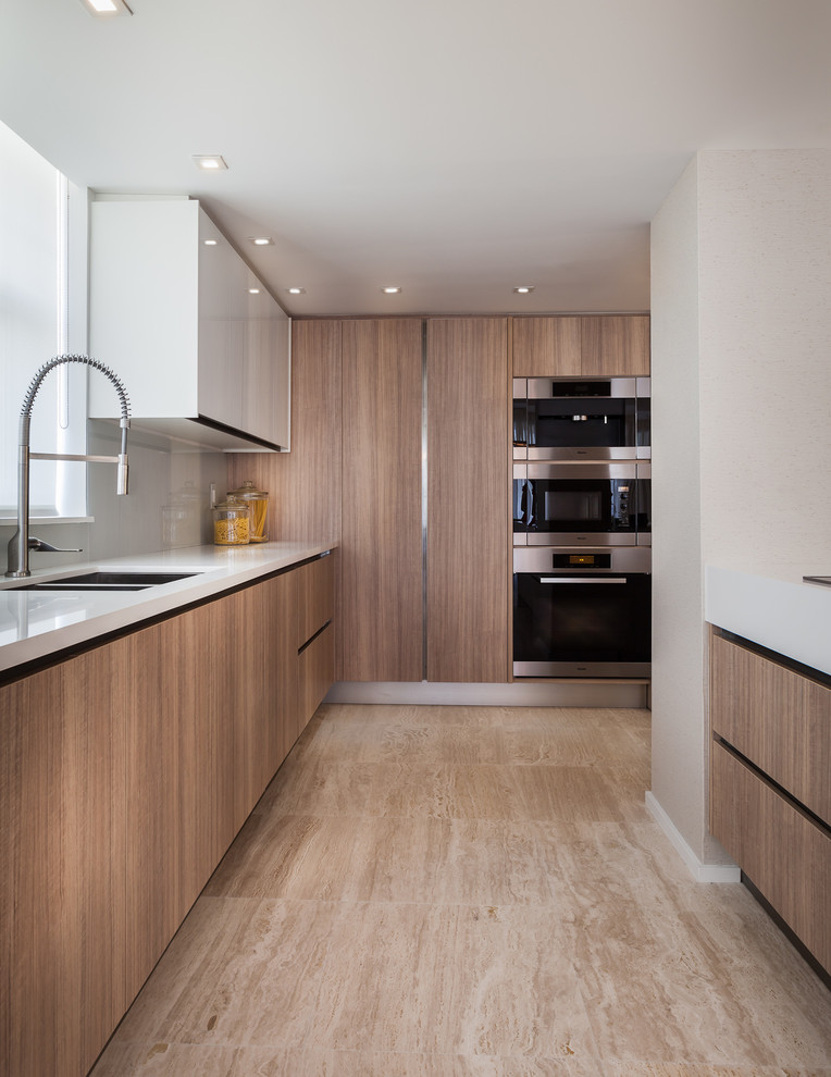 Mid-sized contemporary l-shaped eat-in kitchen in Miami with a double-bowl sink, flat-panel cabinets, white cabinets, solid surface benchtops, white splashback, subway tile splashback, light hardwood floors and with island.