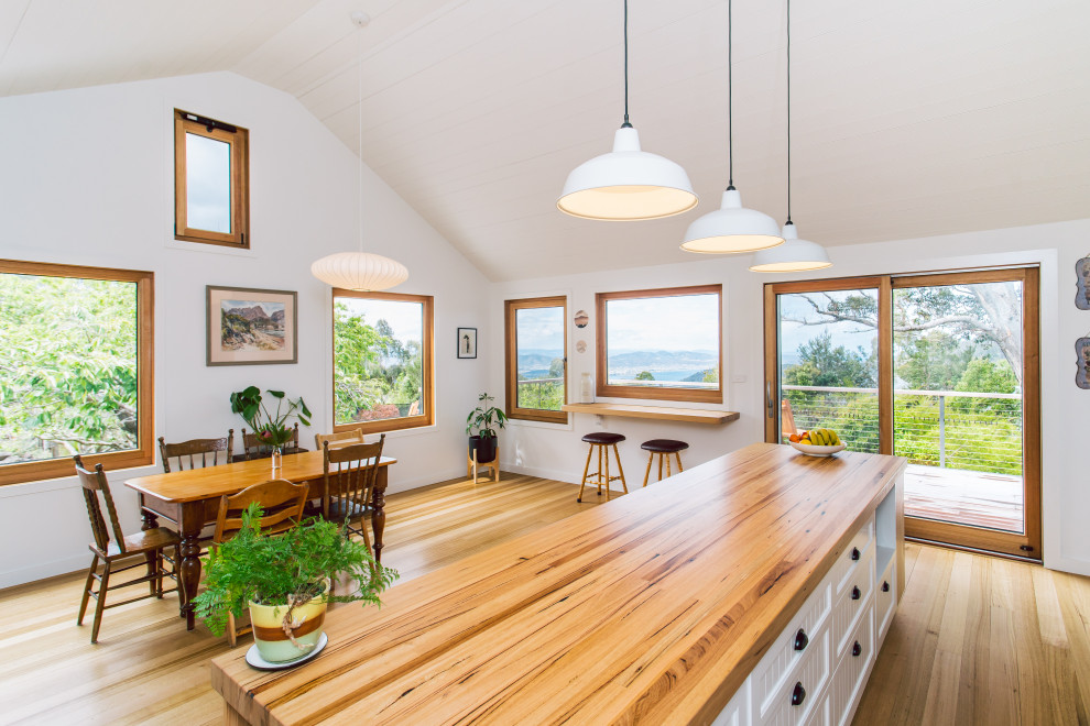 Country kitchen in Hobart with a double-bowl sink, wood benchtops, green splashback, coloured appliances, medium hardwood floors and with island.