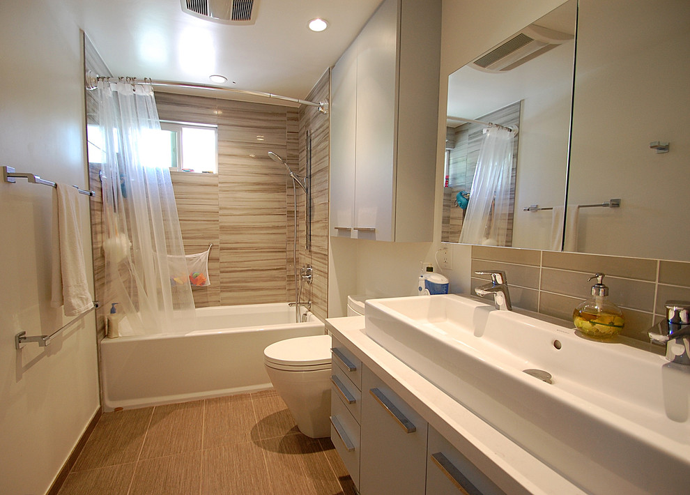 Photo of a mid-sized contemporary master bathroom in Los Angeles with a trough sink, flat-panel cabinets, grey cabinets, engineered quartz benchtops, an alcove tub, a shower/bathtub combo, a two-piece toilet, gray tile, porcelain tile, white walls and porcelain floors.