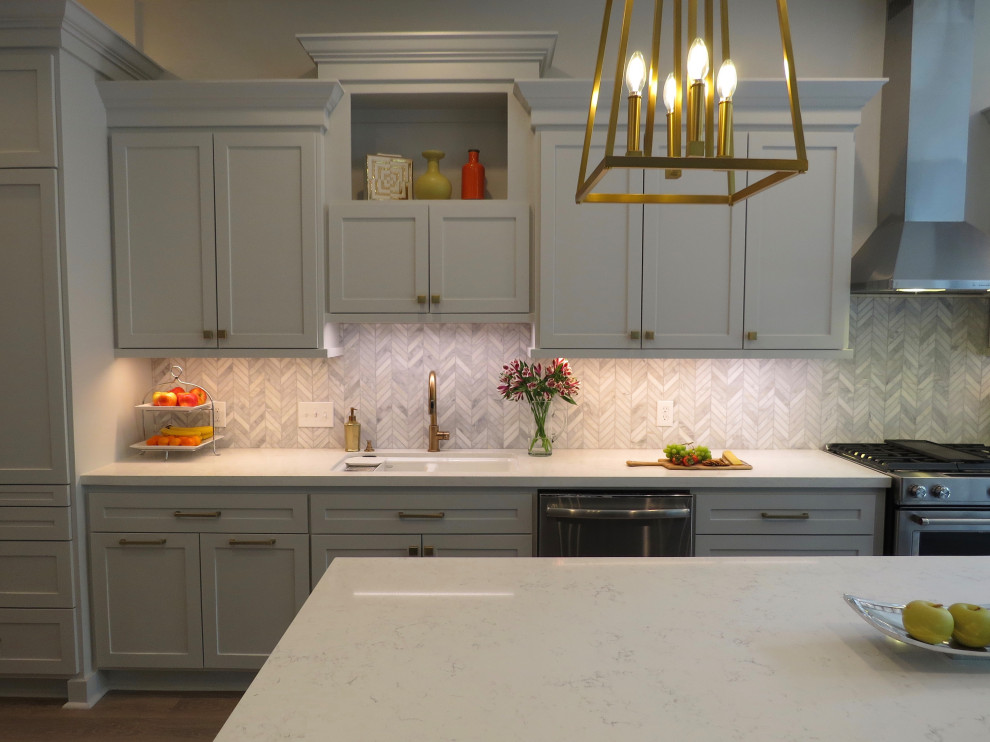 Inspiration for a mid-sized transitional l-shaped eat-in kitchen in Houston with shaker cabinets, grey cabinets, quartz benchtops, white splashback, marble splashback, stainless steel appliances, vinyl floors, with island, beige floor, white benchtop and an undermount sink.