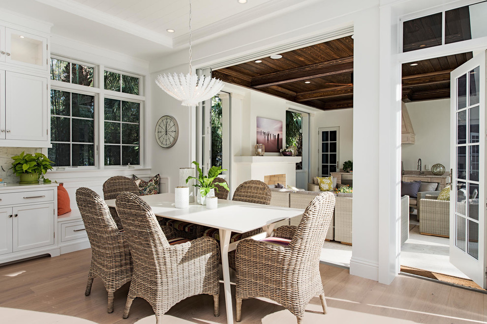 This is an example of a beach style dining room in Miami with white walls, light hardwood floors and beige floor.