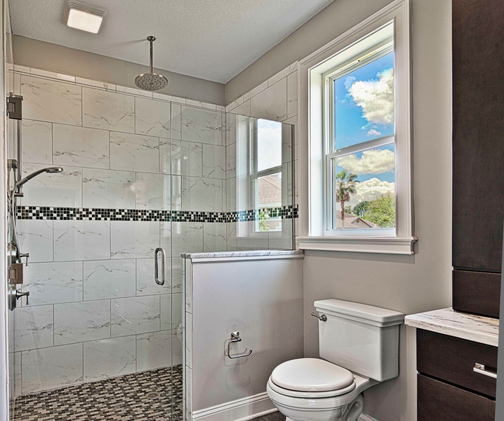 This is an example of a contemporary bathroom in Jacksonville with flat-panel cabinets, dark wood cabinets, a one-piece toilet, white tile, ceramic tile, beige walls, porcelain floors, an undermount sink, engineered quartz benchtops, black floor, a hinged shower door and white benchtops.