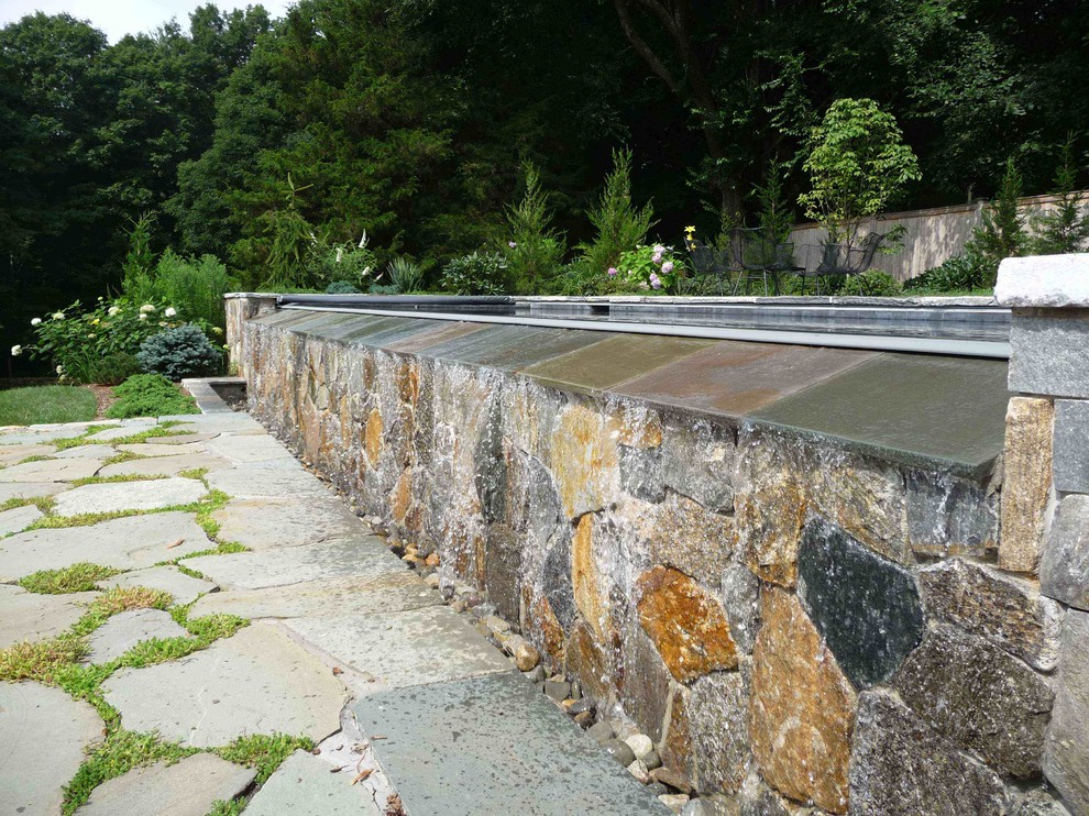 Photo of a beach style backyard rectangular infinity pool in Bridgeport with a water feature and natural stone pavers.
