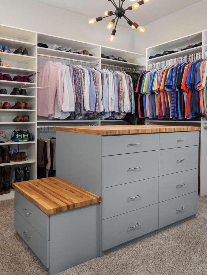 This is an example of a large country men's walk-in wardrobe in Jacksonville with flat-panel cabinets, grey cabinets, carpet and brown floor.