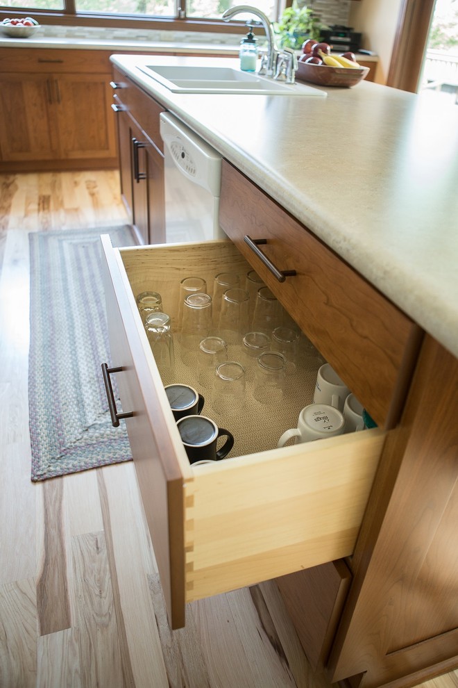 Example of a large transitional l-shaped light wood floor eat-in kitchen design in Cedar Rapids with a double-bowl sink, recessed-panel cabinets, medium tone wood cabinets, laminate countertops, multicolored backsplash, mosaic tile backsplash, white appliances and an island