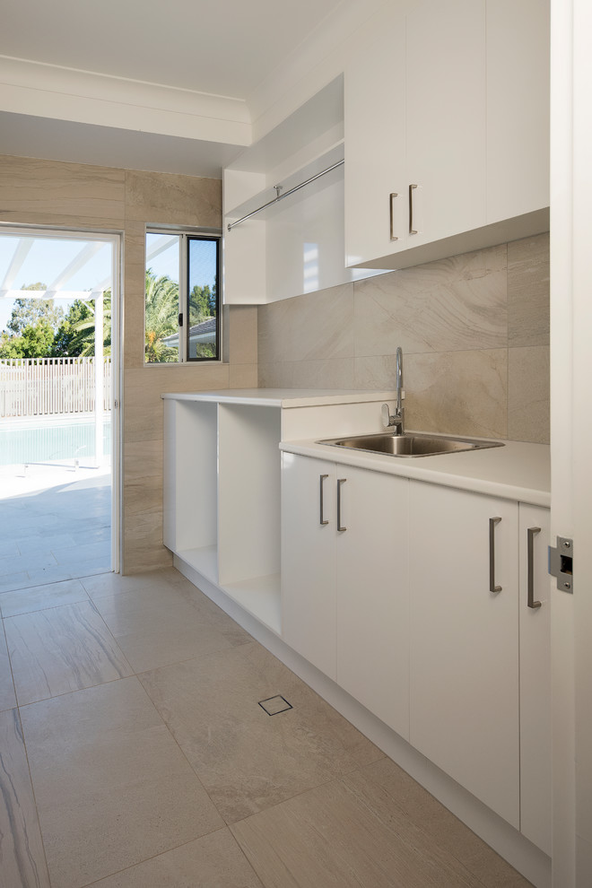 This is an example of a small contemporary single-wall dedicated laundry room in Brisbane with a single-bowl sink, flat-panel cabinets, white cabinets, laminate benchtops, beige walls, ceramic floors, a side-by-side washer and dryer and beige floor.