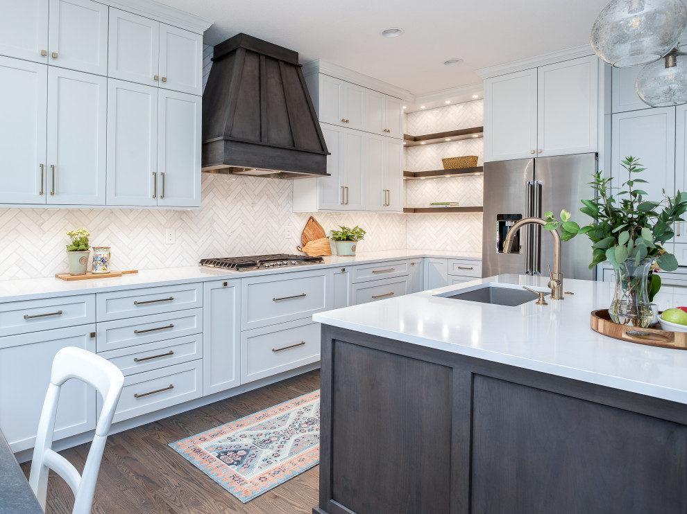 Inspiration for a large transitional galley medium tone wood floor and brown floor open concept kitchen remodel in Denver with an undermount sink, shaker cabinets, white cabinets, quartz countertops, beige backsplash, marble backsplash, stainless steel appliances, an island and white countertops