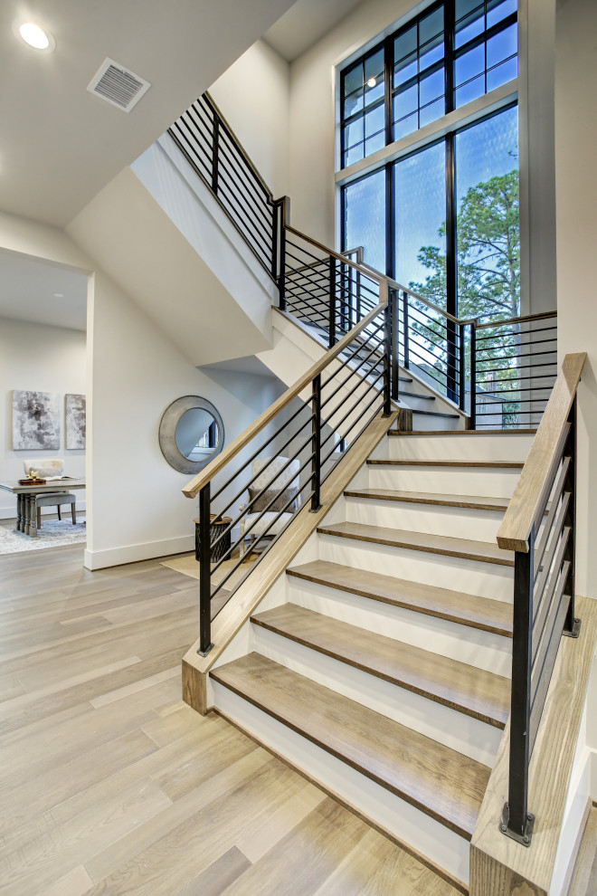 Photo of an expansive contemporary u-shaped mixed railing staircase in Houston with wood risers and a feature wall.