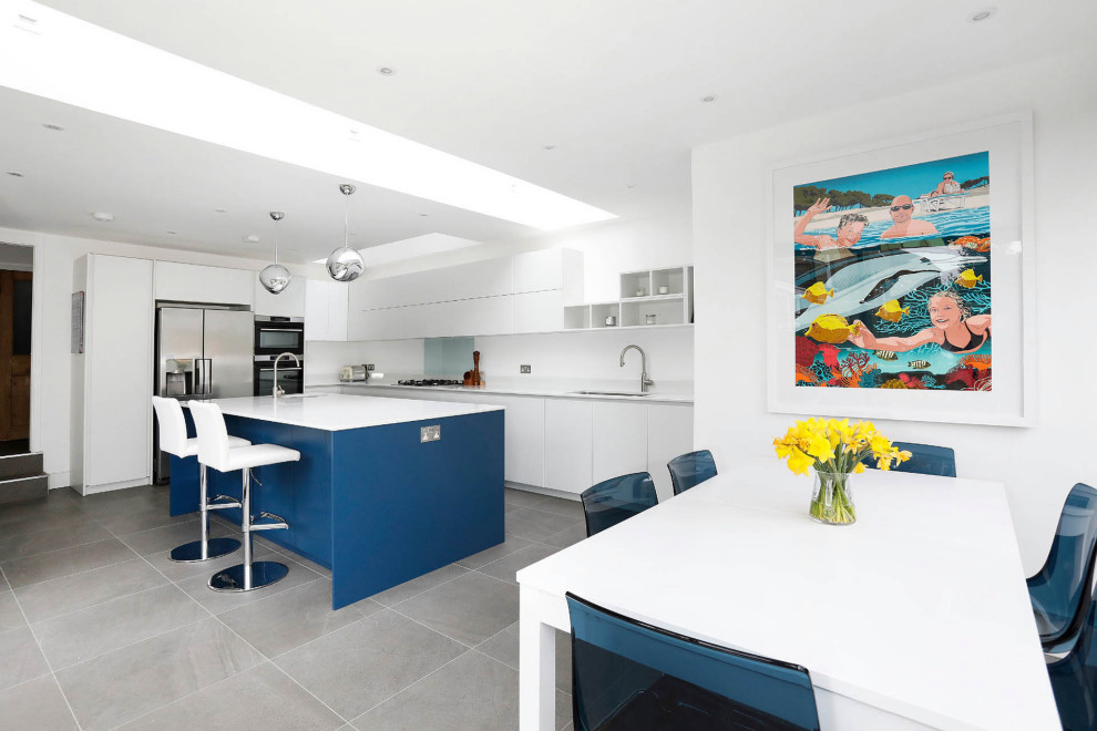 Photo of a large contemporary l-shaped kitchen/diner in London with a double-bowl sink, flat-panel cabinets, white cabinets, an island and white worktops.