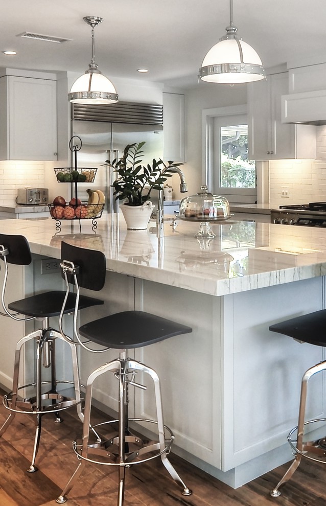 Kitchen pantry - mid-sized transitional l-shaped medium tone wood floor kitchen pantry idea in Orange County with an undermount sink, recessed-panel cabinets, white cabinets, white backsplash, stainless steel appliances, an island, subway tile backsplash, quartzite countertops and white countertops