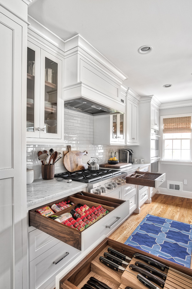 Eat-in kitchen - large transitional l-shaped light wood floor and beige floor eat-in kitchen idea in New York with an undermount sink, beaded inset cabinets, white cabinets, marble countertops, white backsplash, subway tile backsplash, stainless steel appliances, an island and gray countertops