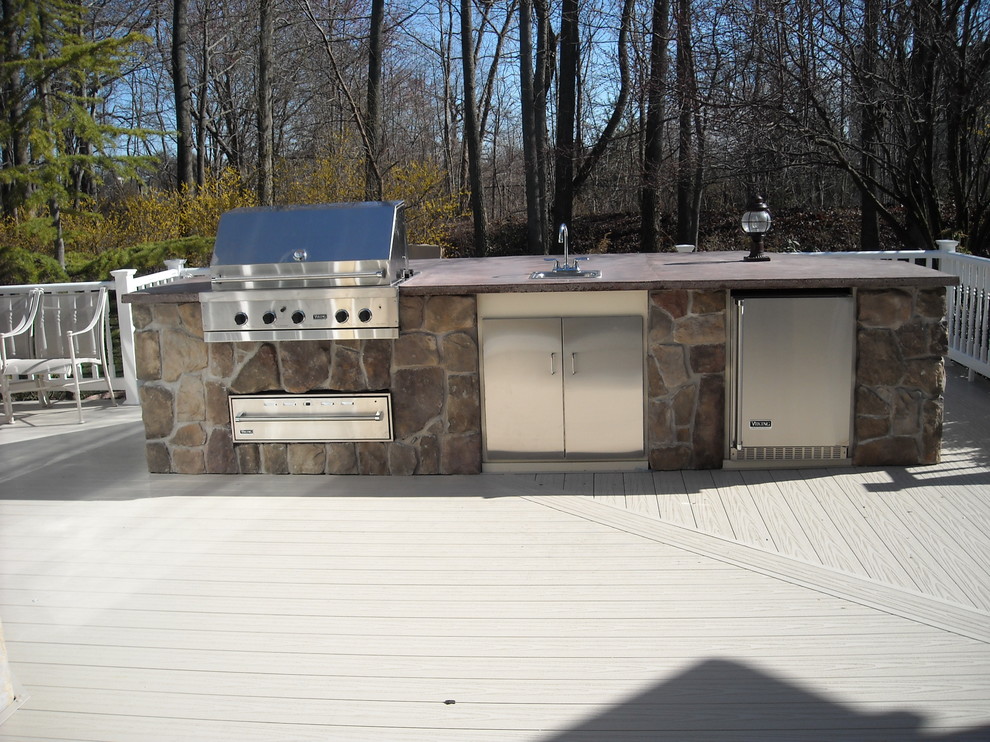 This is an example of a large traditional backyard deck in Philadelphia with an outdoor kitchen and no cover.
