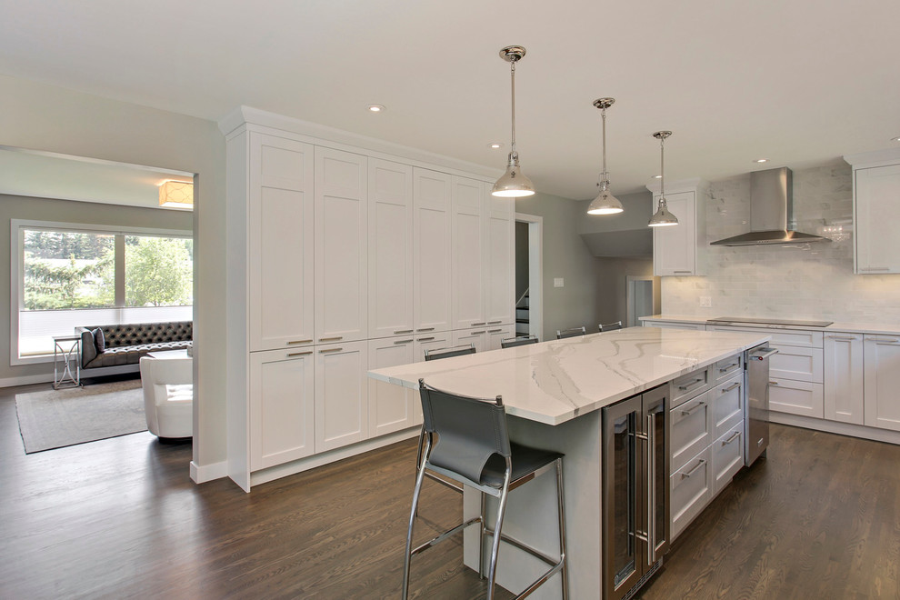 Eat-in kitchen - transitional l-shaped medium tone wood floor eat-in kitchen idea in Calgary with an undermount sink, shaker cabinets, white cabinets, quartz countertops, white backsplash, porcelain backsplash, stainless steel appliances and an island