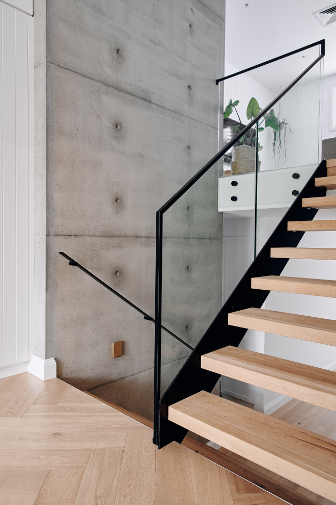 Photo of a large beach style wood u-shaped staircase in Melbourne with open risers, metal railing and decorative wall panelling.