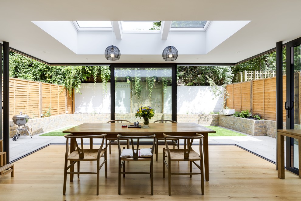 Mid-sized contemporary dining room in London with white walls, light hardwood floors and beige floor.