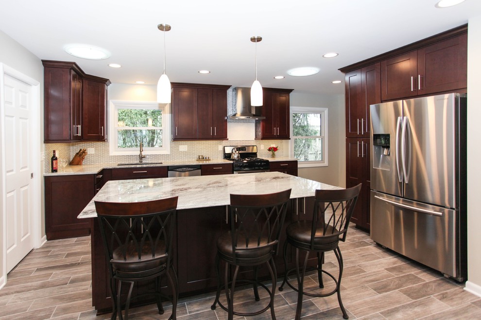 Example of a large transitional u-shaped porcelain tile eat-in kitchen design in Chicago with an undermount sink, recessed-panel cabinets, dark wood cabinets, granite countertops, gray backsplash, glass tile backsplash, stainless steel appliances and an island