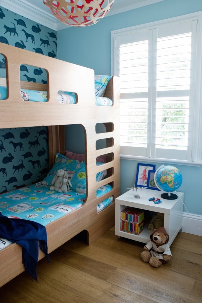 This is an example of a small contemporary kids' bedroom for kids 4-10 years old and boys in Sydney with blue walls and medium hardwood floors.