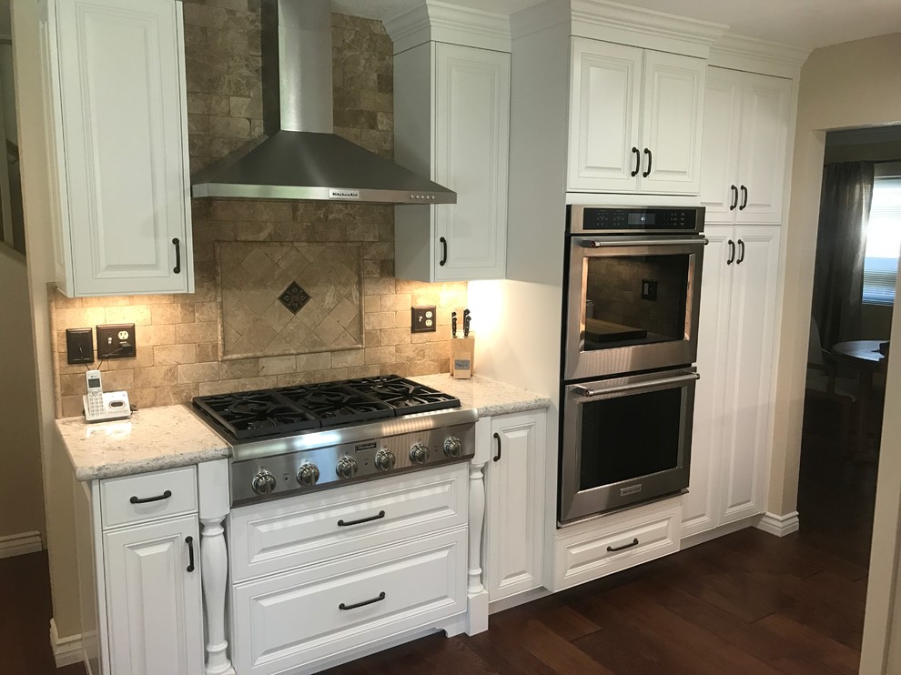 Inspiration for a mid-sized contemporary u-shaped separate kitchen in Los Angeles with a farmhouse sink, raised-panel cabinets, white cabinets, quartz benchtops, stainless steel appliances, dark hardwood floors and no island.